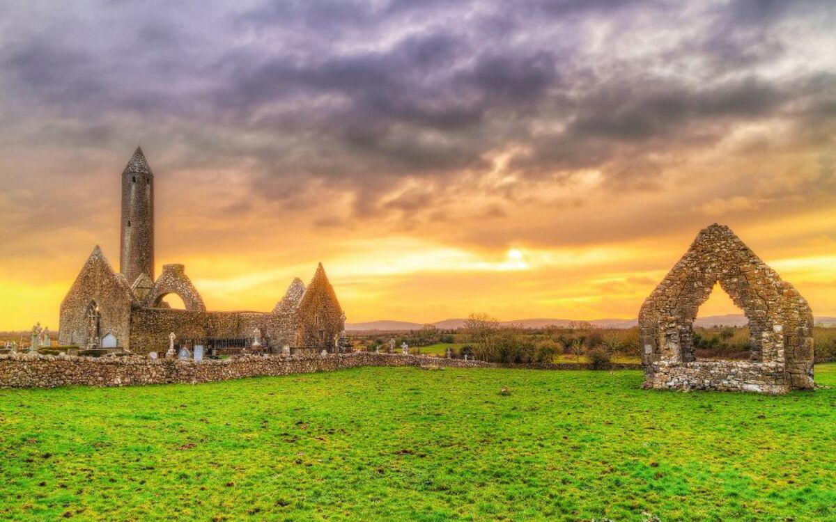 Kilmacduagh monastery with stone tower at sunset, Ireland